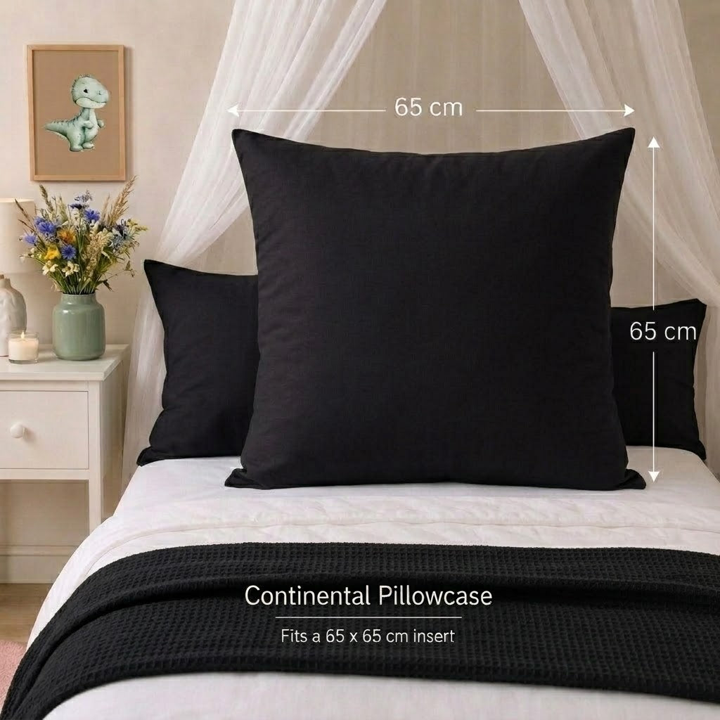 A black continental pillowcase displayed on a bed, shown with white bedding, a black textured throw blanket, and dimension markers indicating a 65 cm by 65 cm size. Text at the bottom reads 'Continental Pillowcase' and 'Fits a 65 x 65 cm insert'.