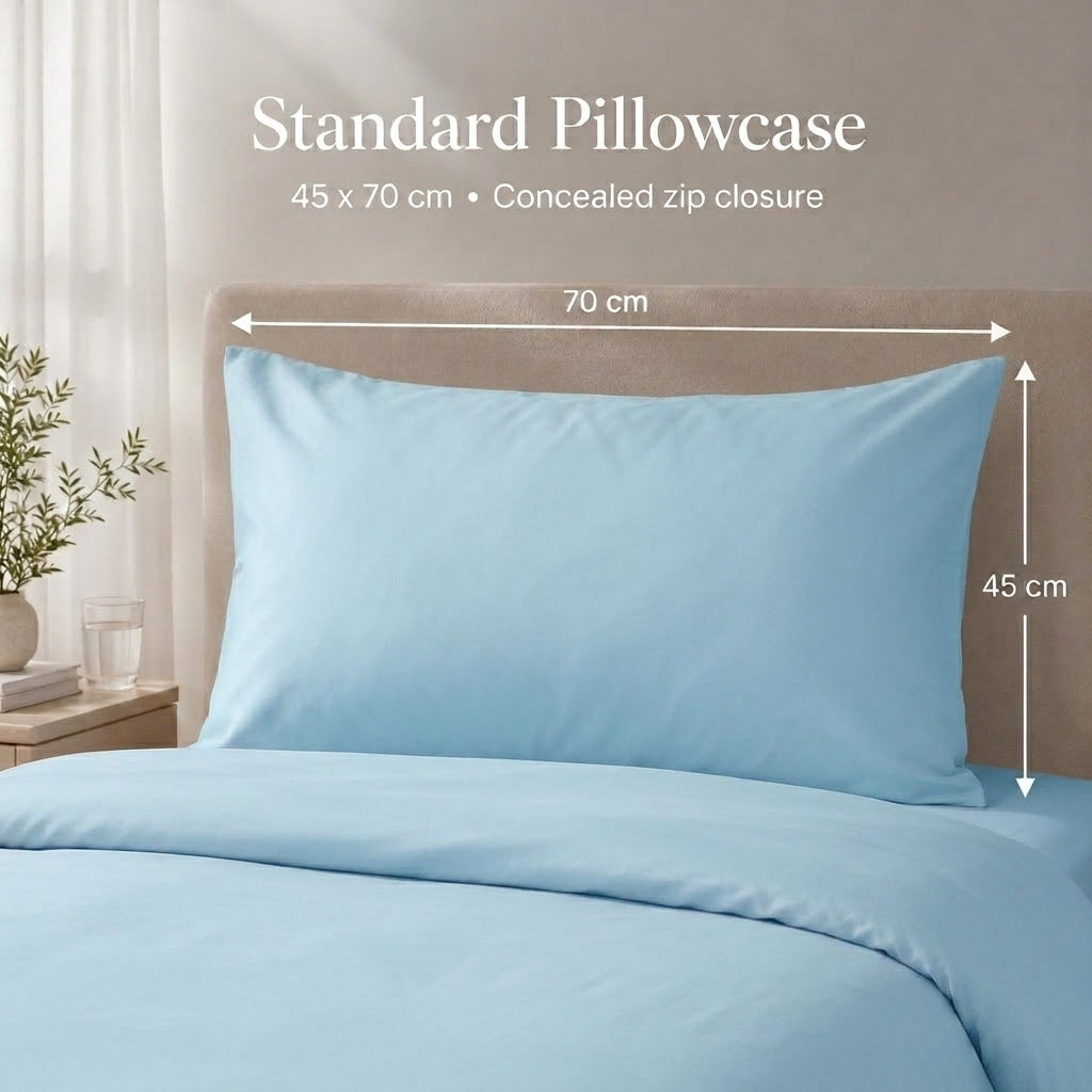 A light blue standard pillowcase shown on a bed with matching bedding, with overlaid text and dimension arrows indicating 70 cm by 45 cm measurements.