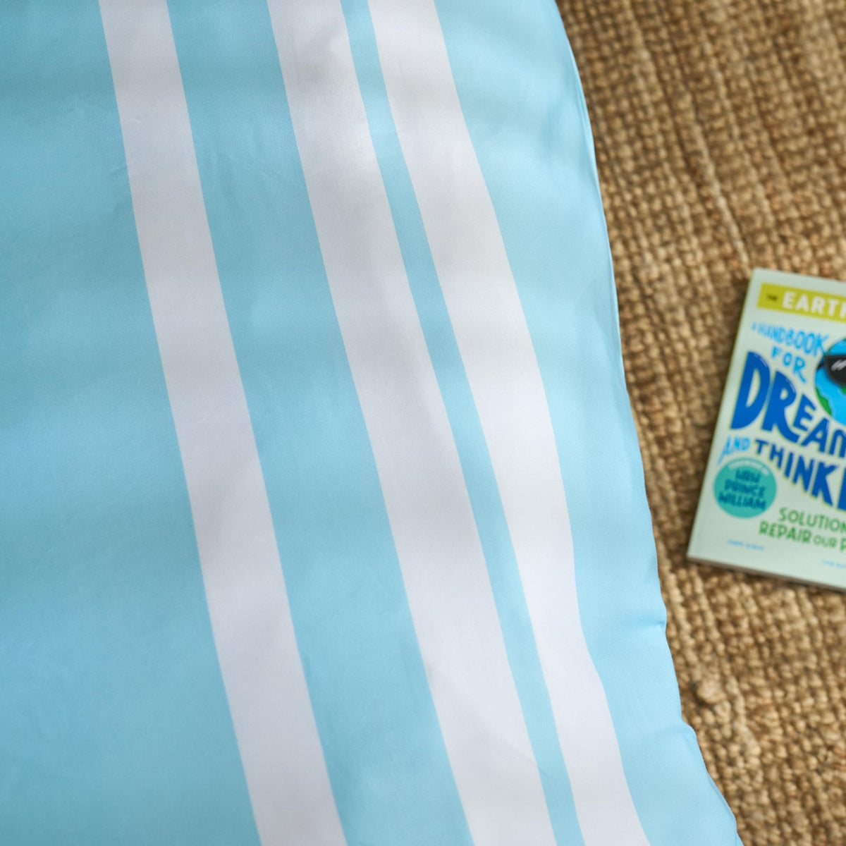 Blue and white striped duvet civer with a box of Dream Thinker on a textured surface