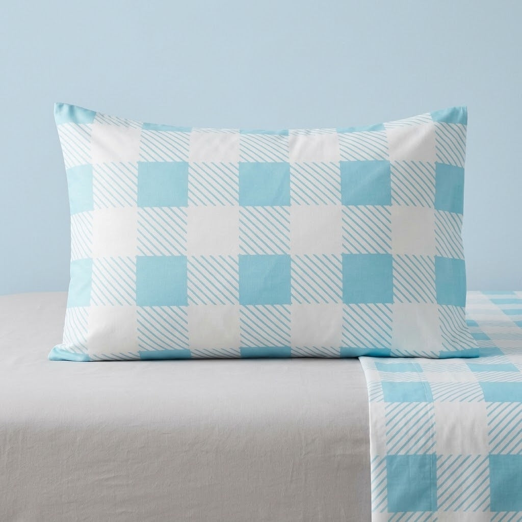 A light blue and white checkered pillowcase resting on a bed with matching checkered bedding against a light blue wall.
