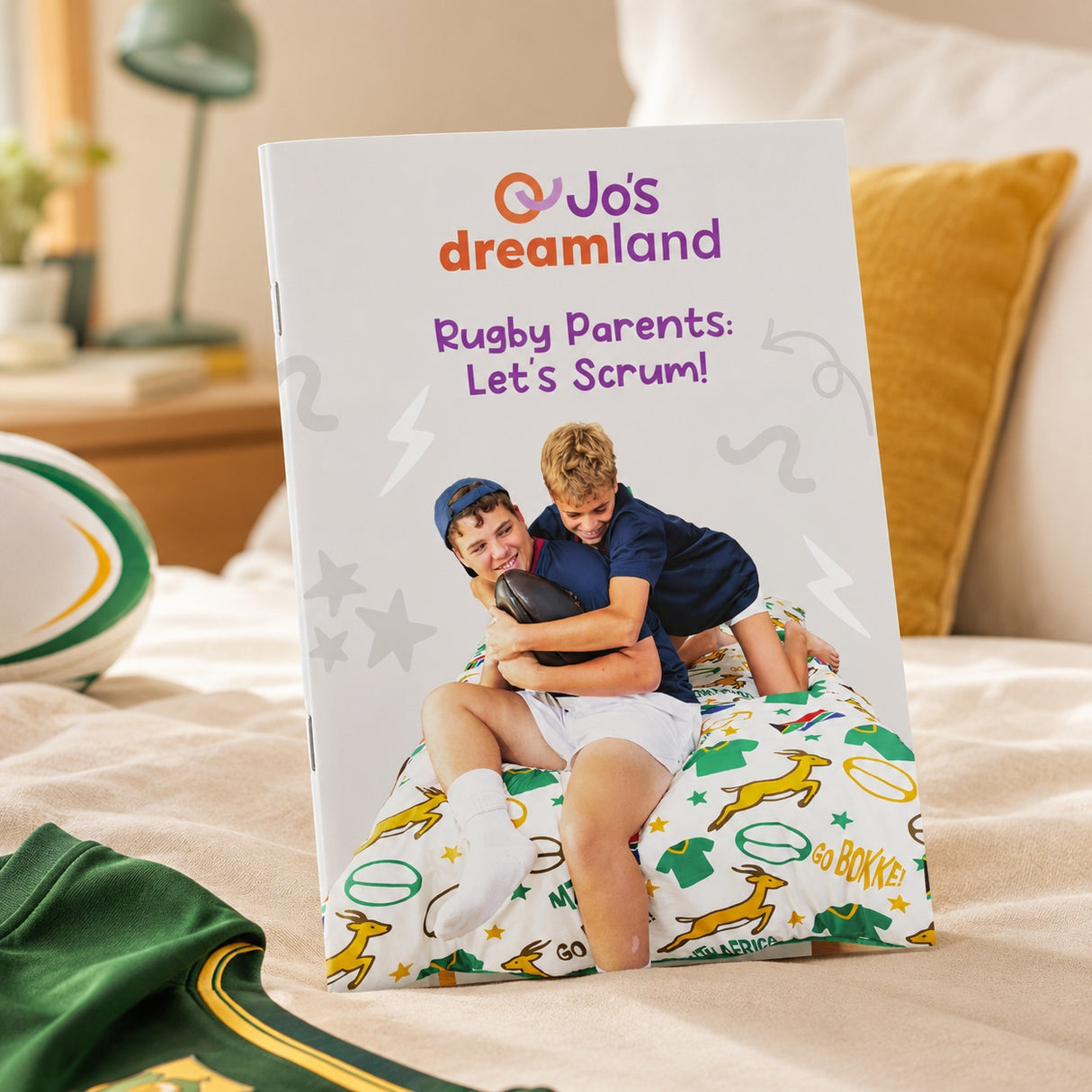 Image of the front cover of a booklet with the title: Ruby Parents: Let's Scrum! on a bed.