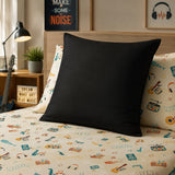 A solid black continental pillow displayed on a bed with a beige and multicolor music-themed patterned sheet and matching pillowcases, set in a cozy bedroom environment.