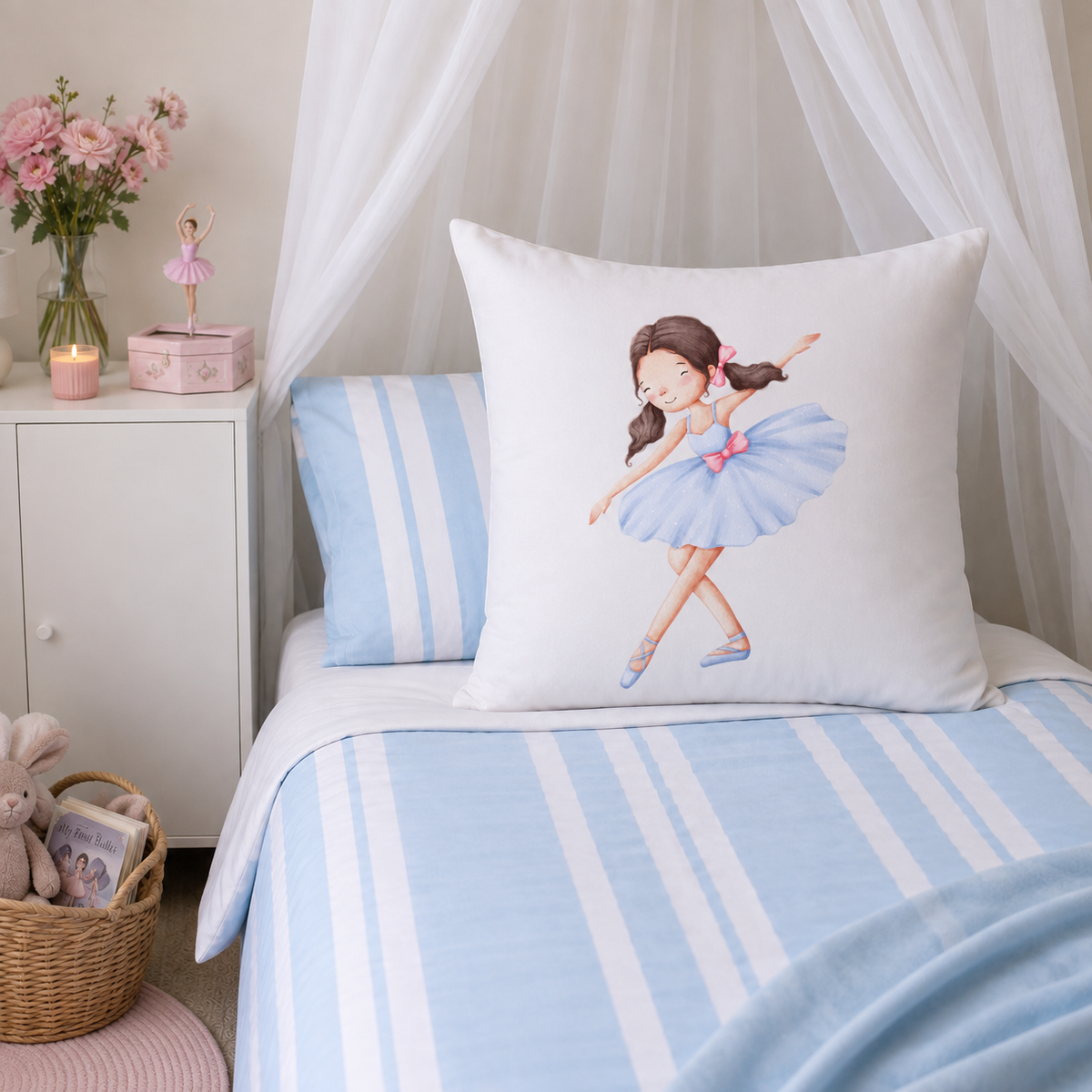 A white contintental pillow featuring a watercolor illustration of a ballerina in a light blue tutu, styled on a bed with light blue and white striped bedding and matching pillows in a soft, nursery-like setting.