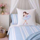 A white contintental pillow featuring a watercolor illustration of a ballerina in a light blue tutu, styled on a bed with light blue and white striped bedding and matching pillows in a soft, nursery-like setting.