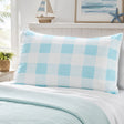 A light blue and white checkered pillow sham on a bed with a matching light blue quilt, styled in a bright bedroom setting.