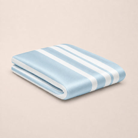 A folded light blue bamboo top sheet with white stripes, displayed on a solid beige background.