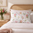 A standard kids pillowcase with a whimsical fairy and floral print, styled on a bed with white linens and a wooden cane headboard in a softly lit bedroom.
