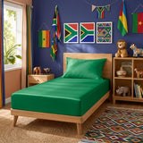 A twin bed dressed in a bright green fitted sheet and pillowcase, placed in a styled children's bedroom with blue walls, South African flag wall art, hanging flags, wooden furniture, and colorful decor.