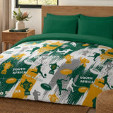 A bed dressed in a South Africa rugby-themed bedding set, featuring a duvet cover and pillowcases with green, yellow, white, and gray sports graphics, silhouettes, and 'SOUTH AFRICA GO BOKKE' text, styled in a bedroom setting.