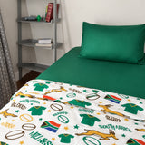 A bed dressed in a green sheet and pillowcase with a white kids duvet cover featuring South African rugby-themed prints, including jerseys, leaping springbok, rugby balls, stars, and 'GO BOCKE!' text, shown in a bedroom setting.
