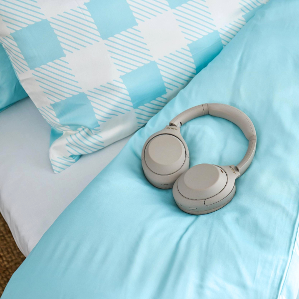 Beige headphones on a bed with blue and white checkered pillows