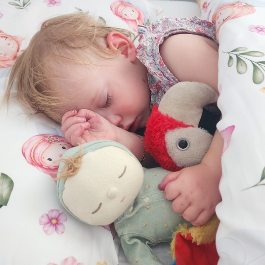 Child sleeping with plush toys on a fairy doona cover