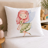 A white continental pillow featuring a colorful watercolor illustration of a fairy with pink hair and green wings, styled on a beige sofa in a cozy bedroom setting.