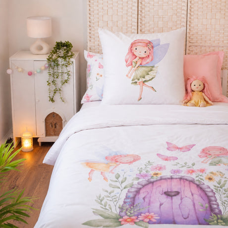 A cozy bedroom scene with a bed styled in a fairy-themed print. The bedding set features a white duvet cover and pillowcases decorated with watercolor illustrations of a purple fairy door, pink butterflies, and a pink-haired fairy.