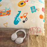 Music-themed duvet cover with colorful designs and 'SING' text, next to a pair of white headphones on a wooden surface.