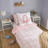 A styled children's bedroom featuring a single bed with a pink and white checkered duvet, a pink octopus continental pillow on a white pillow, and matching pink bedding. The room has lavender walls, white side tables with lamps and a vase of flowers, and a woven jute rug with plush toys.