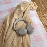 Grey headphones on a camel coloured throw with a pink and white check gingham duvet cover set