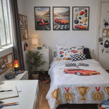 A racing-themed bedroom setup featuring a white bedding set with red sports cars, checkered patterns, and gold trophies, styled in a modern bedroom with three framed race car prints on the wall.