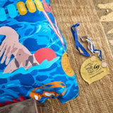 Detail of swimming themed duvet cover on bed with swimming cap and medal on floor next to it.