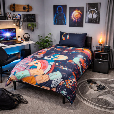 Room interior with a bed featuring a colorful technology themed duvet cover, desk with laptop, and wall art.