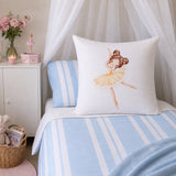 A white continental decorative pillow featuring a watercolor illustration of a ballerina in a yellow tutu, styled on a bed with light blue and white striped bedding in a soft, nursery-like setting.